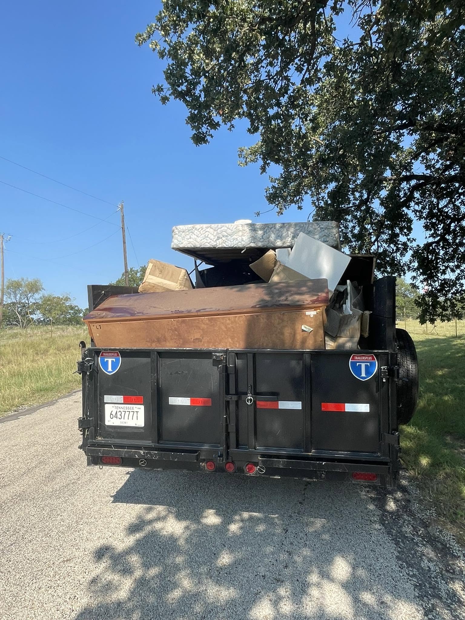 Dump trailer loaded with move-out leftovers and cardboard from a property turnover