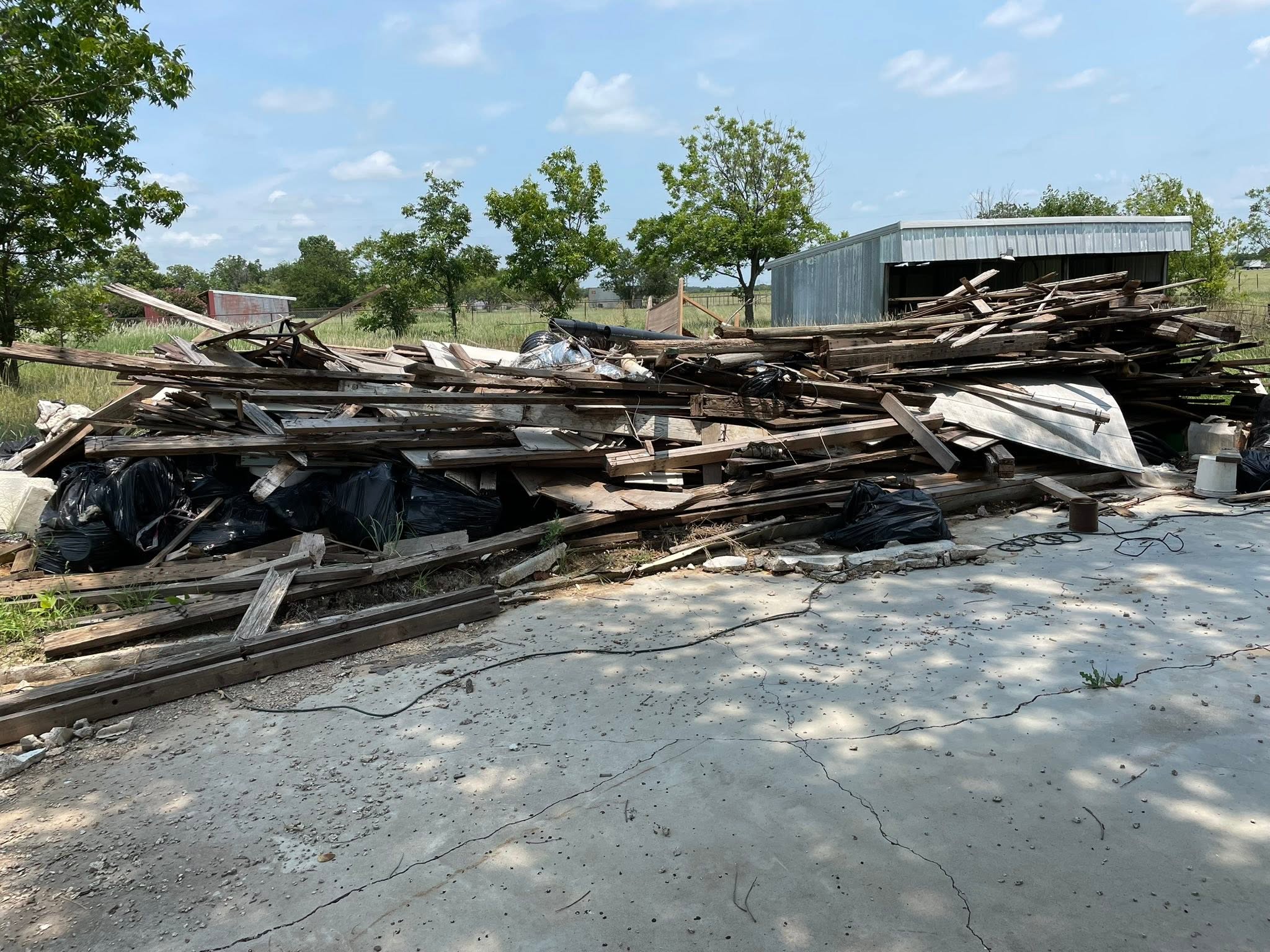 Large pile of lumber and mixed debris on a property before cleanout